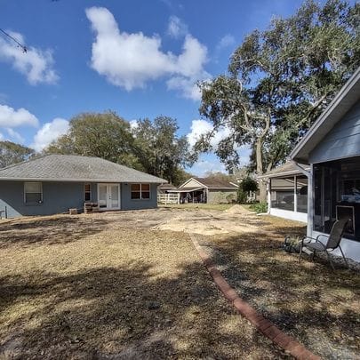 Backyard view with two houses and a partially cleared lawn, showcasing Absolute Outdoors LLC’s landscape renovation and yard maintenance in Odessa, FL.