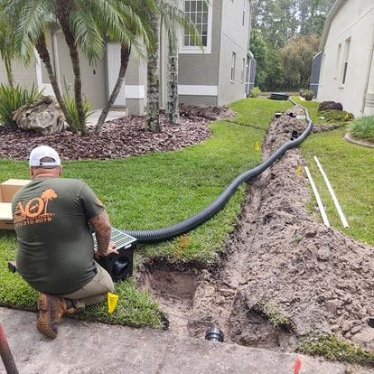 Landscaping professional installing a pipe in a yard.