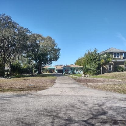 Two houses with a wide open yard and a long driveway, showing the comprehensive landscaping and property maintenance by Absolute Outdoors LLC in Odessa, FL.
